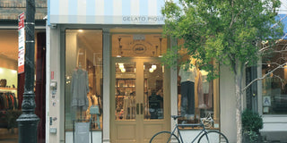 Street view of Gelato Pique store entrance with clothing displays and a bicycle parked outside.
