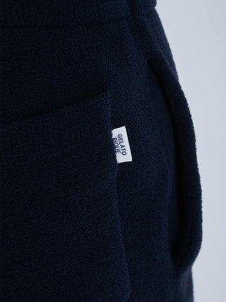Close-up of navy blue lounge shorts with a pocket and white label tag, highlighting soft texture and detailed craftsmanship.