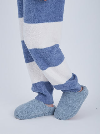 Person wearing blue and white striped Baby Moco men's lounge pants with blue slippers showcasing soft plush material.