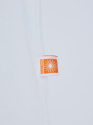 EAMES House of Cards orange logo tag on white fabric of men's long sleeve tee