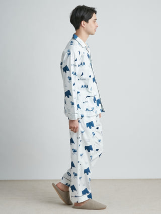 Side view of a man wearing EAMES Chair Motif Men's Lounging Pajamas in white with blue prints, made from 100% recycled cotton.