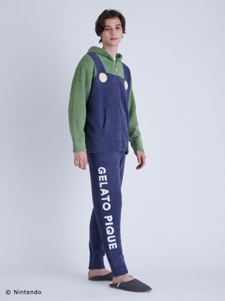 Man wearing Luigi costume loungewear set, featuring green hooded pullover and blue pants with "Gelato Pique" text, inspired by Super Mario.