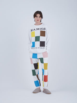 Model wearing EAMES Air Moco Logo Men's Knit Pullover with colorful patchwork design, showcasing modern elegance and recycled polyester material.