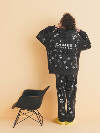 Person wearing EAMES mens hoodie with dot pattern beside a modern chair, showcasing stylish comfort and unique design.