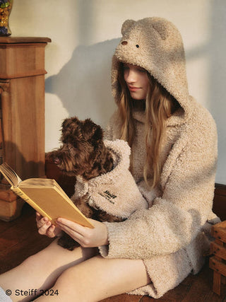Person reading a book wearing cozy loungewear with a dog in matching outfit, exemplifying sustainable fashion choices.