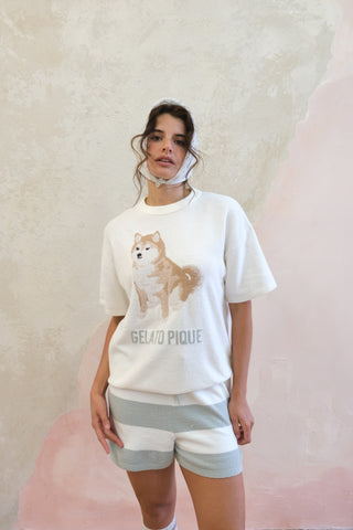 Woman wearing cream Shiba Pullover and light blue striped shorts loungewear by Gelato Pique USA, featuring Shiba Inu design.