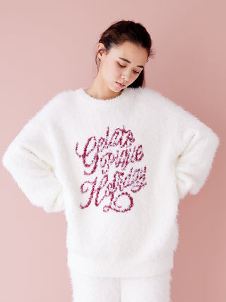 Woman wearing white feather pullover sweater with festive text, showcasing cozy and elegant holiday fashion.