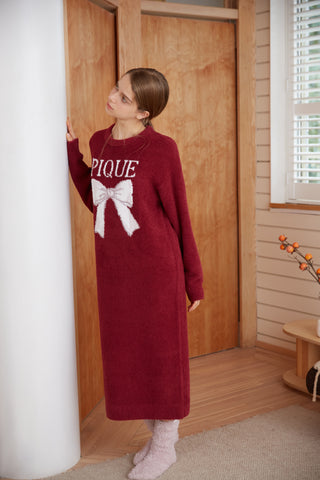 Woman wearing a burgundy Ribbon Jacquard Dress with white bow design, cozy indoor setting.