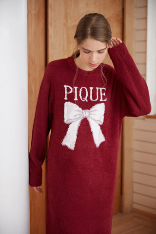 Woman wearing a burgundy Ribbon Jacquard Dress with a white bow design, showcasing Gelato Pique's cozy, luxurious fabric.