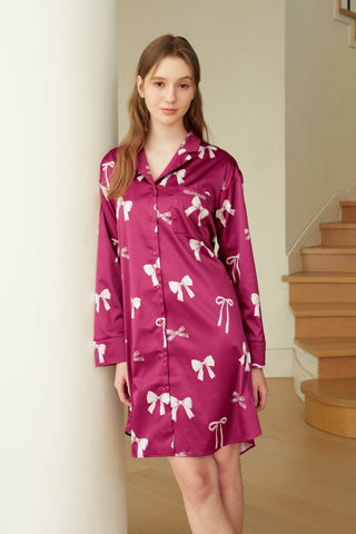 Woman wearing a ribbon pattern satin shirt dress with a silky texture, showcasing elegance and comfort in vibrant pink with bow prints.