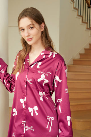 Woman wearing a Ribbon Pattern Satin Shirt Dress with a vibrant bow print, standing indoors.