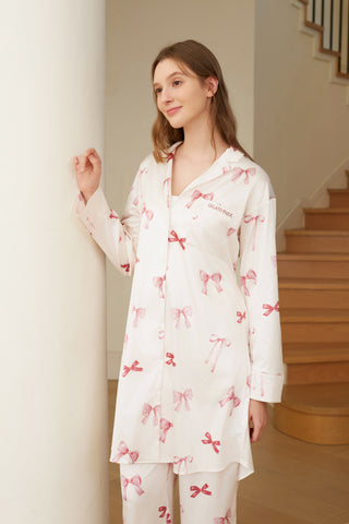 Woman wearing a Ribbon Pattern Satin Shirt Dress with pink bow prints, standing near stairs, showcasing elegant loungewear fashion.