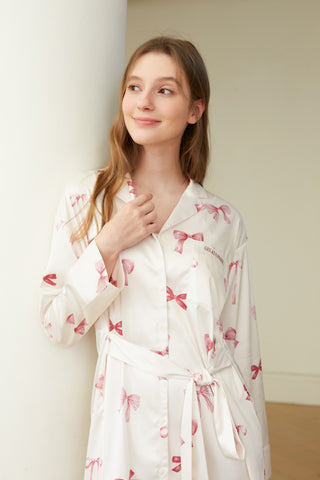 Woman wearing Ribbon Pattern Satin Shirt Dress with pink bow design, showcasing elegant loungewear style in a casual setting.