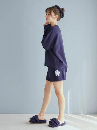 Woman wearing Airy Moco Tiered House Slippers and navy loungewear, standing against a light gray wall.