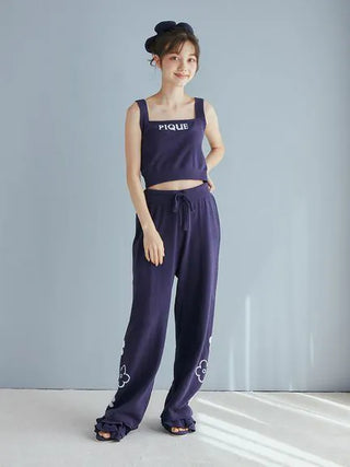 Woman wearing Gelato Pique's navy Airy Moco Flower Logo Jacquard Cropped Tank Top with matching pants, standing against a light background.