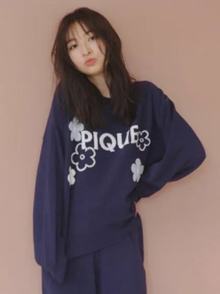 Woman wearing Airy Moco Flower Logo Jacquard Pullover Sweater with floral details and 'PIQUE' text, in blue color.