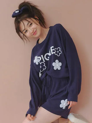 Woman in Gelato Pique Airy Moco Flower Logo Jacquard Pullover Sweater, navy with flower design, posing indoors.