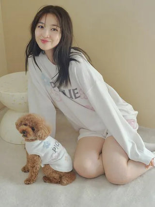 Woman wearing Airy Moco Flower Logo Jacquard Pullover Sweater with a small poodle in matching outfit, lounging indoors.