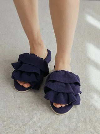 Person wearing Airy Moco Tiered House Slippers in dark blue, showing unique ruffled design on a light carpeted floor.