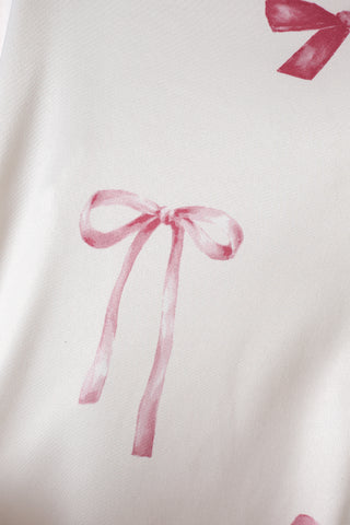 Close-up of pink ribbon pattern on satin fabric from a shirt dress, showcasing a playful and elegant design.