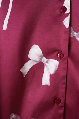 Close-up of Ribbon Pattern Satin Shirt Dress in burgundy with white bow design and matching buttons.