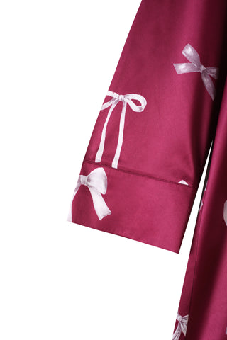 Close-up of Ribbon Pattern Satin Shirt Dress sleeve, showcasing vibrant bow print on luxurious satin fabric.