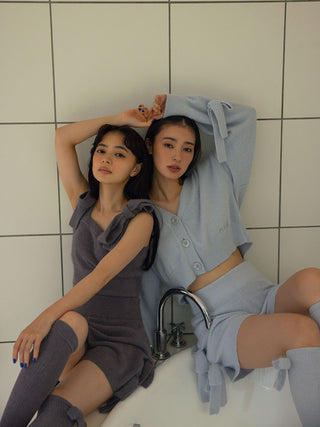 Two women wearing cozy Ribbon Lounge Shorts with ribbon accents, sitting in a tiled room, exuding playful and feminine style.