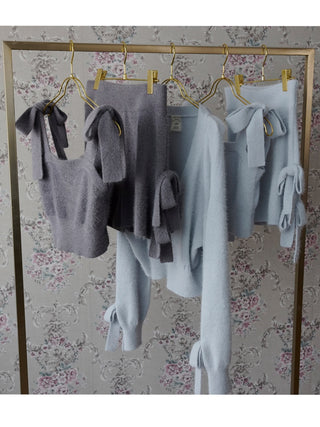 Plush ribbon lounge shorts and tops in light blue and grey hanging on gold hangers, showcasing cozy and playful design.