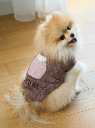 Fluffy dog wearing a CAT&DOG Cupcake Sleeveless Pet Clothes, featuring a cute design on a wooden floor.