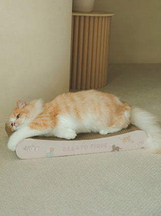 Orange cat lounging on Gelato Pique Cat Pattern Scratching Board in a beige room setting.