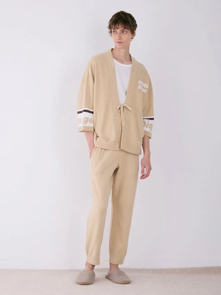 Model wearing MENS Air Moco Logo Jacquard Lounge Pants and top in beige, showcasing relaxed fit and comfort with slippers.