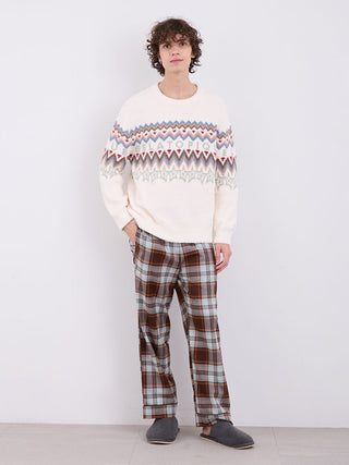 Man wearing a Mens Powder Fair Isle Jacquard Pullover Sweater with winter pattern, paired with plaid pants and slippers.