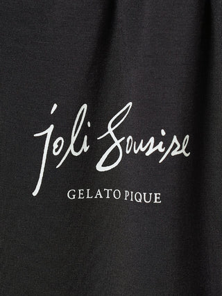 Close-up of Gelato Pique logo with 'joli sourire' text on black background fabric.