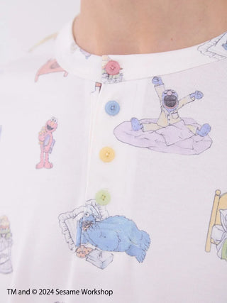 Close-up of men's Sesame Street all-over print Henley-neck pullover with colorful buttons and character illustrations.