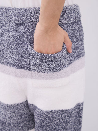 Close-up of hand in pocket of men's powder melange striped fuzzy pajama pants in grey and white.