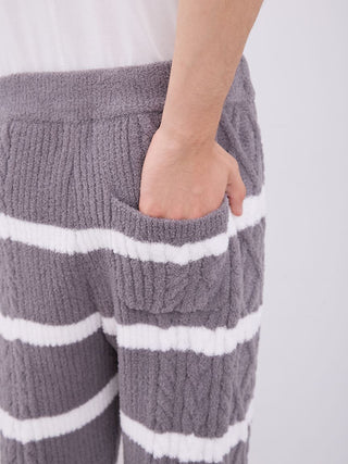 Close-up of striped cable knit pajama pants with hand in pocket, highlighting cozy fabric and detailed Aran pattern design.