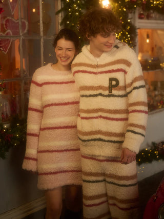 Couple wearing cozy striped pajamas with fluffy texture for holiday season comfort and style, standing in festive setting.