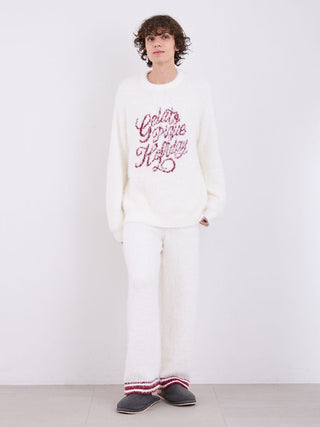 Model wearing cozy white pajama set with festive lettering, showcasing holiday fashion and comfort.