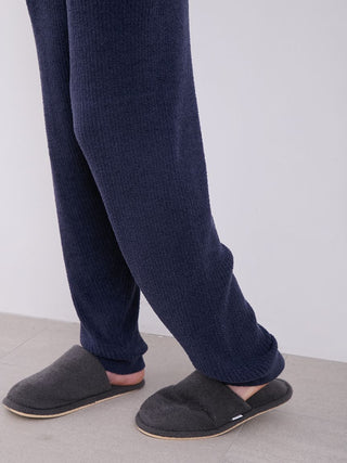 Man wearing MEN's Hot Smoothie Rib Long Pants in navy blue, showcasing rib-knit texture and paired with dark grey slippers.