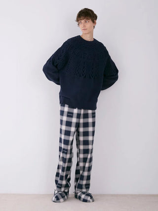 Model wearing men's Air Moco Aran pullover sweater with classic Aran knit in navy, paired with checkered pants.