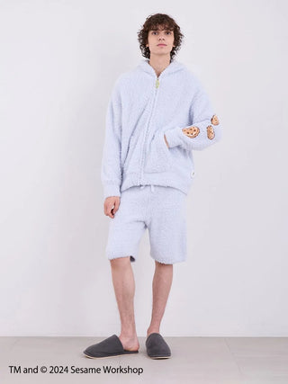 Men's Cookie Monster loungewear set from Sesame Street, featuring a fluffy hoodie and shorts, worn by a model indoors.