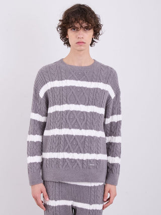 Man wearing grey and white Aran cable knit pullover sweater with horizontal stripes, crafted from soft Baby Moco fabric by Gelato Pique.