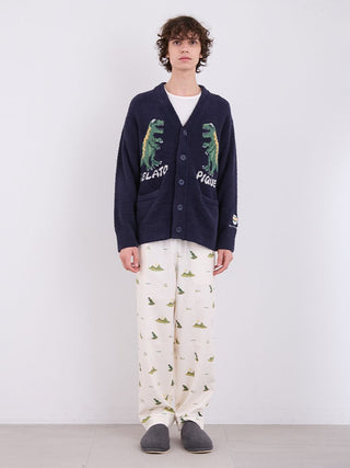 Man wearing MEN'S Powder Dinosaur Jacquard Knit Cardigan with dinosaur design by Gelato Pique, paired with printed pants and slippers.