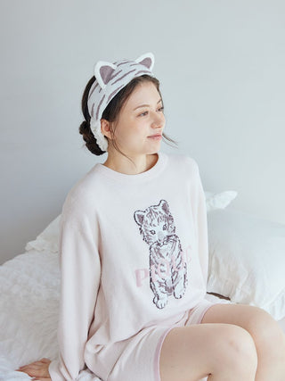 Woman wearing a White Tiger Headband, perfect for skincare routines, paired with cozy pajamas with a tiger print, sitting on a bed.