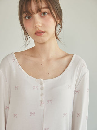 Woman in off-white premium loungewear with pink pattern by Gelato Pique USA, featuring a stylish wide neckline and button details.