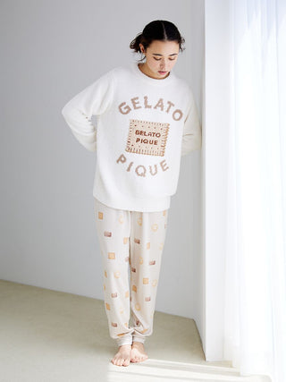 Woman wearing Gelato Pique biscuit pattern waffle pajama pants, standing by a window, showcasing comfort and style in soft knit fabric.