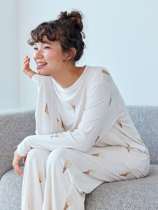 Woman sitting on couch wearing Gelato Pique Ice Cream Pattern Long Sleeve Pajama Shirt, featuring all-over ice cream cone print.