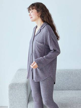 Woman in cozy gray pajamas standing next to a sofa, showcasing a relaxing homewear style.