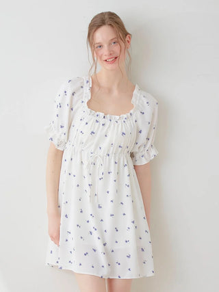 Model wearing a Small Floral Smocked Mini Dress with blue flowers on a white fabric, featuring puff sleeves and a gentle, feminine look.