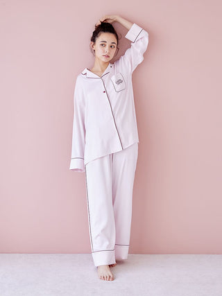 Model wearing luxurious piping satin pajama pants and top against a pink background, showcasing elegance and comfort for relaxation.